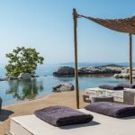 Infinity pool sun loungers with towels and Aegean sea view